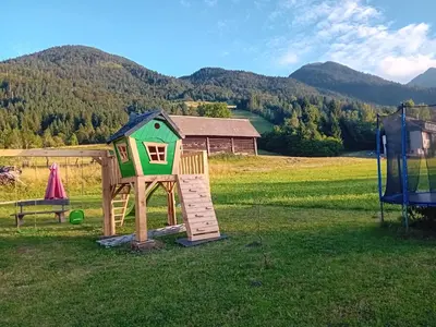 a play house in a field with a bench at Tubej apartments in Bohinj