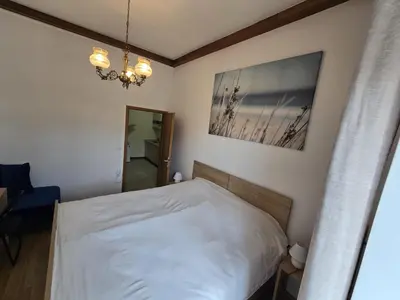 a bedroom with a white bed and a chandelier at Ludanov apartma in Radlje ob Dravi