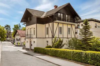 a large white house with a black roof at Guest House The Hive in Bled