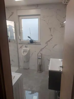 a bathroom with a sink and a urinal and a window at APARTMA Črnomelj in Črnomelj