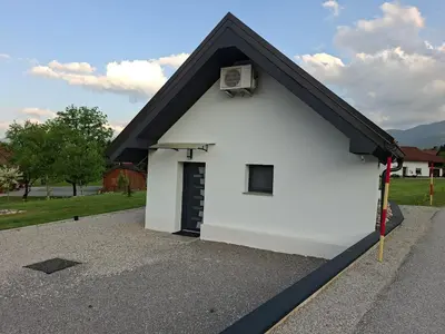 a small white building with a black door at Sun House Luka in Radmirje