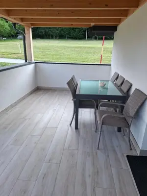 a patio with a table and chairs on a deck at Sun House Luka in Radmirje
