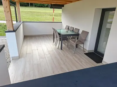 a patio with a table and chairs on a deck at Sun House Luka in Radmirje