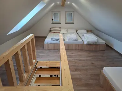 a attic room with a bed and a staircase at Sun House Luka in Radmirje