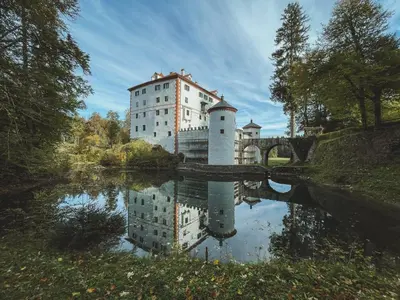 a castle with its reflection in a body of water at Snežnik castle estate in Stari Trg pri Ložu