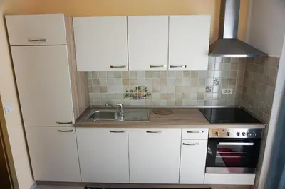 a kitchen with white cabinets and a sink at Apartments Kravanja in Bovec