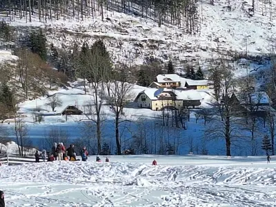 a group of people standing in the snow next to a house at Luna's House in Zgornje Jezersko