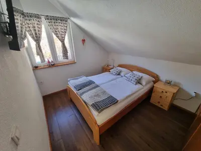 a small bedroom with a bed and two windows at Luna's House in Zgornje Jezersko