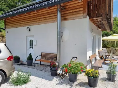 a small white house with a bench and flowers at Luna's House in Zgornje Jezersko