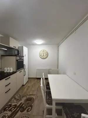a kitchen with a white table and a clock on the wall at Apartment Tunnel in Hrušica