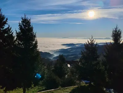 a view of a mountain with the sun in the sky at Apartma Pohorc - Kostanj in Pohorje