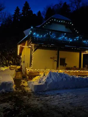 a house with christmas lights on the side of it at Apartma Pohorc - Kostanj in Pohorje