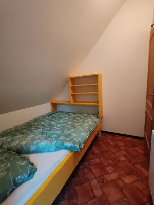 a small bedroom with a bed and a shelf at Apartma Pohorc - Kostanj in Pohorje