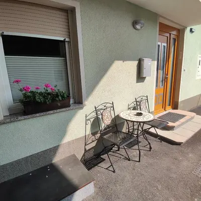 a patio with chairs and a table and a window at Frane House in Knežak