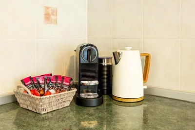 a counter with a coffee maker and a basket of utensils at Apartment in the Village in Petrovče