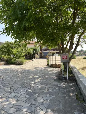 a stone driveway with a sign in front of a tree at Suzi Apartments in Lokev