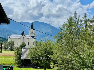 a large white church with a mountain in the background at Studio Lilly in Bohinj