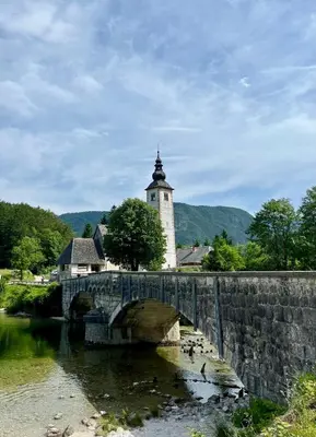 a stone bridge with a church and a tower at Studio Lilly in Bohinj