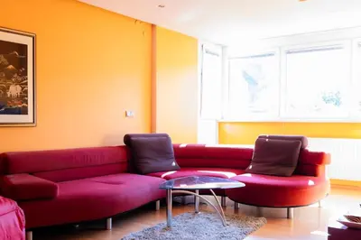 a living room with a red couch and two chairs at The Color Loft in Ljubljana
