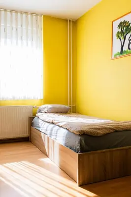 two beds in a room with yellow walls and a window at The Color Loft in Ljubljana
