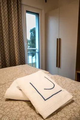 a white towel sitting on a bed with a window at LJ Apartments - Šempeter pri Gorici in Šempeter pri Gorici