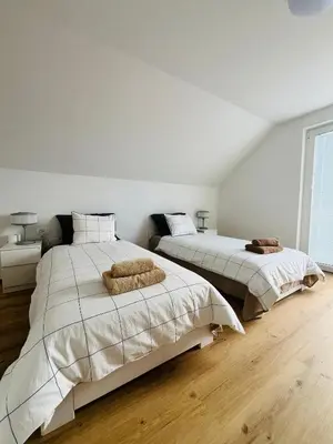 two beds in a bedroom with white walls and wooden floors at Apartma DUDI