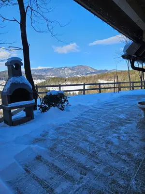 a snow covered patio with a tree and a fence at Hiška pod krošnjami