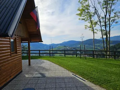 a walkway next to a building with mountains in the background at Hiška pod krošnjami