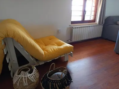 a room with a yellow ottoman and two baskets at Green view apartment in Sežana