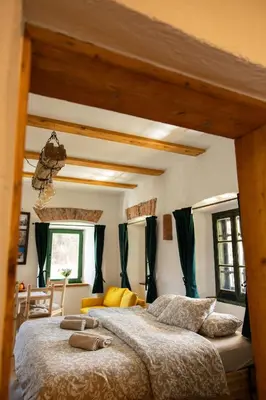 a bedroom with two beds and a room with windows at Golavškov mlin - Eco Heritage Boutique Stay in Prebold