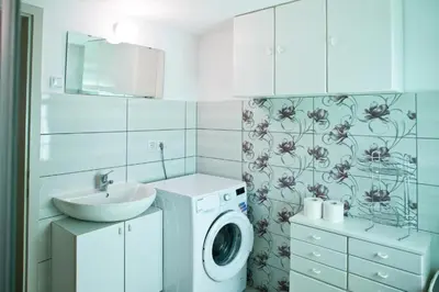 a bathroom with a washing machine and a sink at Počitniška hiša pod RAJHOVKO in Ljubno