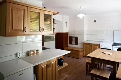 a large kitchen with wooden cabinets and a table at Počitniška hiša pod RAJHOVKO in Ljubno