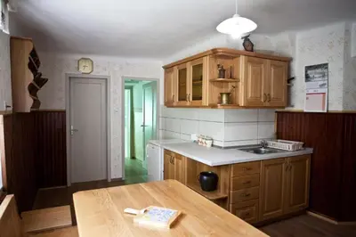 a kitchen with wooden cabinets and a wooden table at Počitniška hiša pod RAJHOVKO in Ljubno