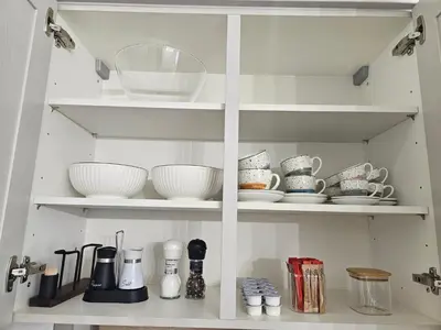 a white cabinet filled with dishes and bowls at Apartma VINT in Ajdovščina