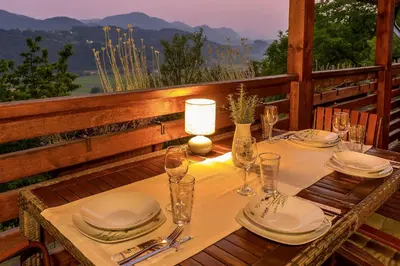 a table with plates and wine glasses on a porch at Herbal Apartment Marjetka in Šentjur