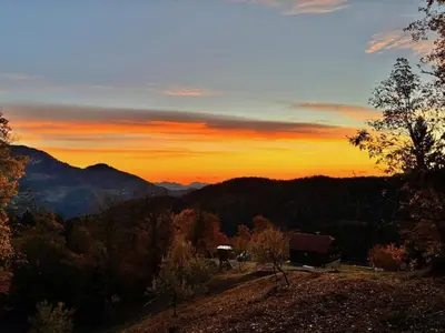 a sunset in the mountains with a house on a hill at Sedmakovo - Počitniška hiša v naravi - Ljubno ob Savinji in Ljubno