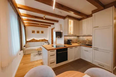 a kitchen with white cabinets and a living room at Menart Estate apartments in Cerklje na Gorenjskem