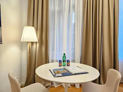 a white table with bottles and chairs in front of a window at Urban Nest Wolfova by the Triple Bridge in Ljubljana
