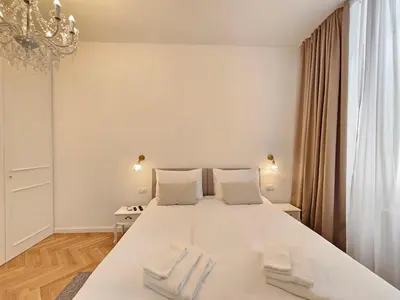 a bedroom with a large white bed with two white towels at Urban Nest Wolfova by the Triple Bridge in Ljubljana