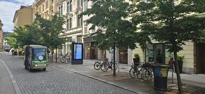 a small bus driving down a city street with bikes at Urban Nest Wolfova by the Triple Bridge in Ljubljana
