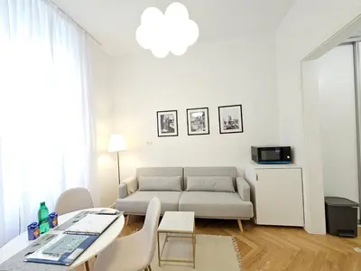 a white living room with a couch and a table at Urban Nest Wolfova by the Triple Bridge in Ljubljana