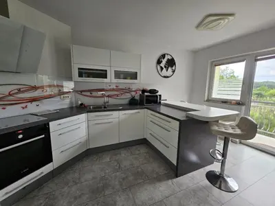 a kitchen with white cabinets and a chair in it at Designer apartment in nature in Vojnik
