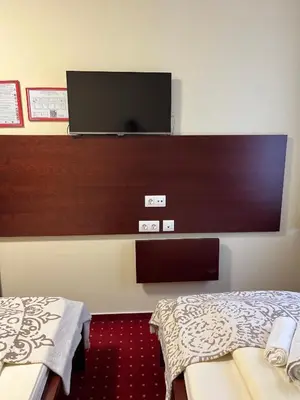 a hotel room with two beds and a flat screen tv at Prenočišča Zvezda in Ljutomer