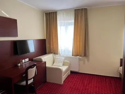 a hotel room with a chair and a desk at Prenočišča Zvezda in Ljutomer