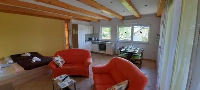 a living room with two orange chairs and a kitchen at Apartment Murka in Begunje na Gorenjskem