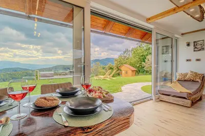 a table with food and wine glasses and a large window at Vineyard cottage Pri mali luži in Trebelno