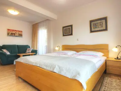a bedroom with a large wooden bed and a chair at Apartments Mira in Bled