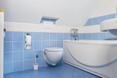 a blue tiled bathroom with a toilet and a sink at Apartma Igor in Bohinj