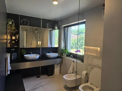 a bathroom with two sinks and a toilet and a window at Rozna Retreat in Nova Gorica