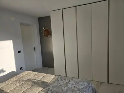 a bedroom with a bed and white cabinets at Rozna Retreat in Nova Gorica